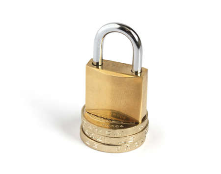 locked closed padlock standing on a pile of coins isolated on white backgroundの写真素材
