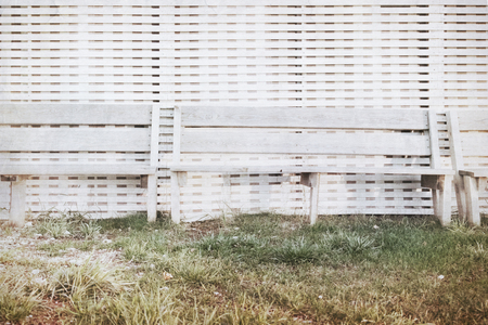 Bench stand at a wall from white colored boards at sunset by the seaの写真素材