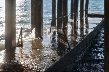 Concrete breakwater with concrete columns during a storm in sunny day on the sea coastの写真素材