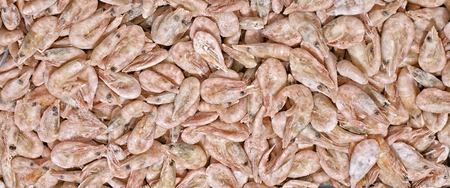 A lot of frozen shrimp lie on the counter of the store