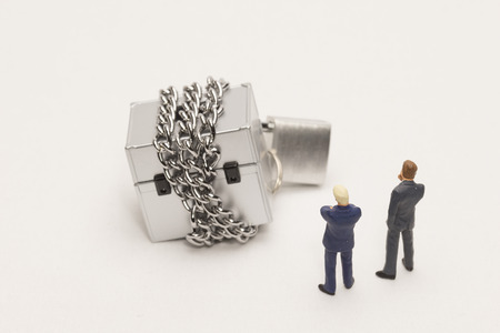 Businessman looking at boxes tied with chainsの写真素材