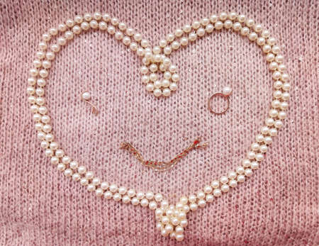 background soft thick woolen fabric of gentle pink color with small sequins with cones and white pearls in the shape of a heart for valentine's day or Valentine's day and a greenの写真素材