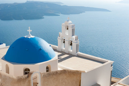 The bell on the blue roof building on the island of Santoriniの写真素材