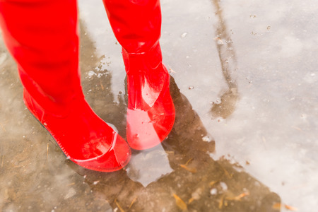 Feet in red rubber boots in the spring poolの写真素材