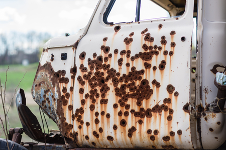Rusty bullet holes in the door start the truck in the background of natureの写真素材