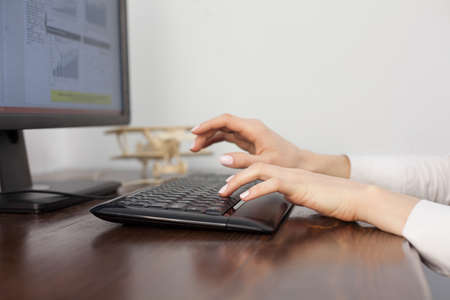 Female hands typing on keyboard on wooden table
