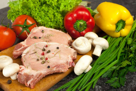 raw steak and vegetables on cutting boardの写真素材
