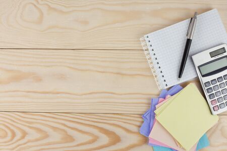 notebook, calculator  and pen on wooden tableの写真素材