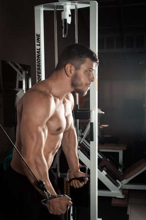 Bodybuilder Is working on his chest with cable crossover In a dark gym