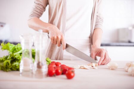 Woman cutting mushrooms in kitchenの写真素材