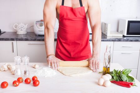muscle man cooking pizza in the kitchenの写真素材