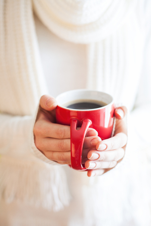 Woman holds a winter cup close up. Woman hands  holding a cozy knitted mug. Winter and Christmas time concept.の写真素材