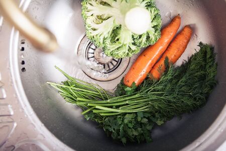 washing vegetables in sink in kitchen