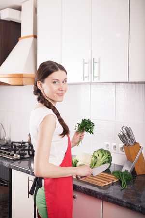 Smiling woman making healthy food in kitchen. Dieting vegetarian concept.の写真素材