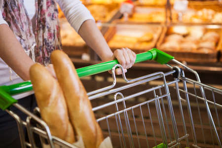 Woman with trolley buying fresh bread in bakery