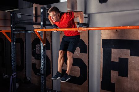 Strong man doing pull ups in gym