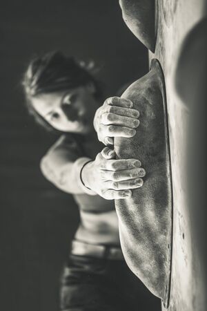 Young woman training on practice climbing wall indoorの写真素材