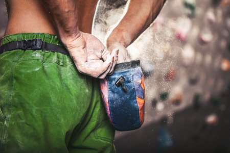 Climber man coating his hands in powder chalk magnesium and preparing to climb indoor, close-upの写真素材