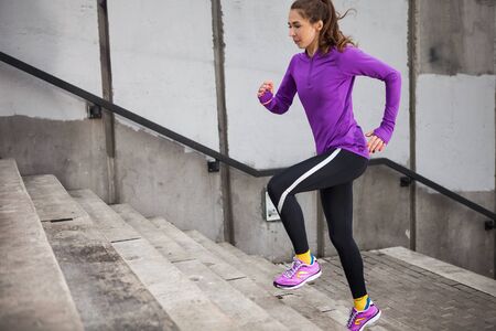 Slim attractive sports women running against a concrete wall