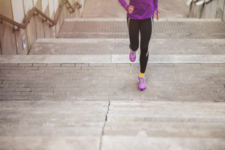 young sporty woman running upstairs on city stairsの写真素材