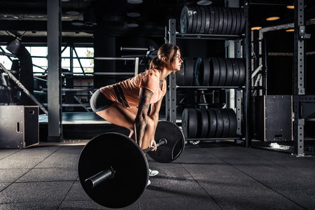 Muscular young fitness woman doing heavy  deadlift exercise in gymの写真素材