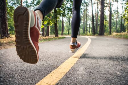 Sporty woman running on road at sunrise. Fitness and workout wellness concept.の写真素材