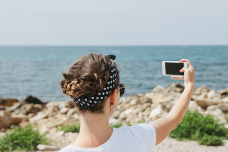 Beautiful young woman  doing selfie in the summer day near the seaの写真素材