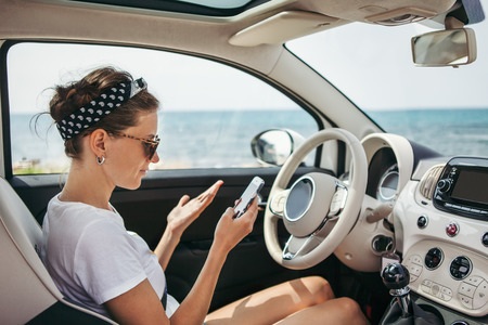 Young woman traveler on car using GPS navigator on her phone.の写真素材