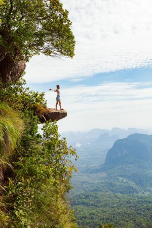 Young woman traveler standing on a cliff and enjoying the view