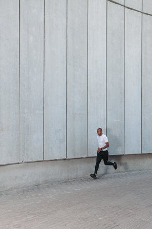 Man running in the urban space with  concrete wall on background. Healthy lifestyleの写真素材