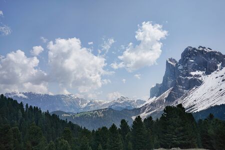 Rocky mountain landscape over the green forest, blue sky with scenic white cloudsの写真素材