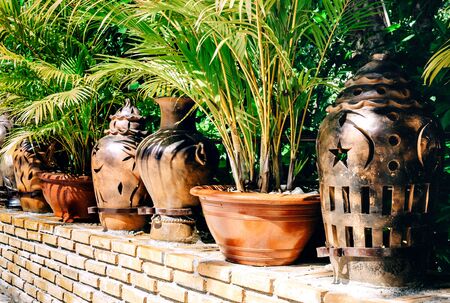 Pots made in Vietnam and standing on the territory of the pagoda among green trees and shrubs with...