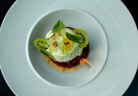 Chocolate cake with cognac in the restaurant. The cupcake is decorated with a soufflé of kiwi, mint leaves and fruit jellyの写真素材