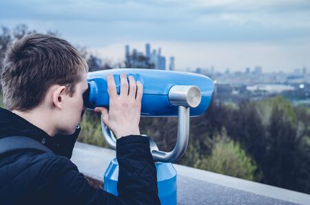 The guy is looking through binoculars through the urban landscape on the observation deckの写真素材