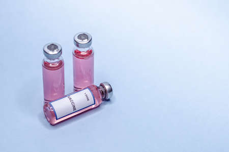 Syringe with a needle and a dose of vaccine inside. Vaccine in glass bottles on a white backgroundの写真素材