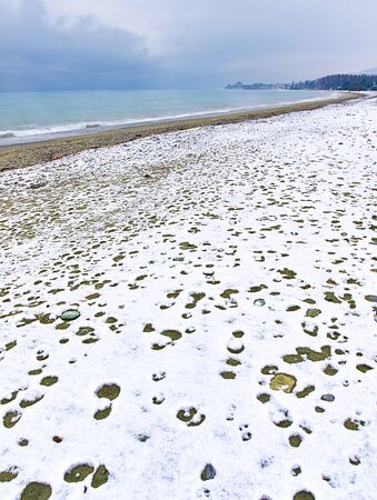 Snow covered beach, sea and cloudy sky, winter landscape from Litohoro, Pieria, Greece.の写真素材