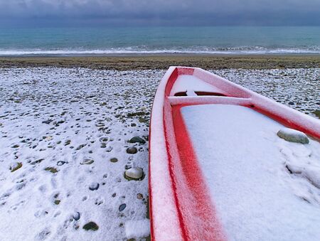 Snow covered red boat, on a beach in Pieria central Macedonia Greece.の写真素材