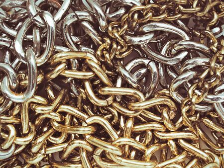 Tangled gold and silver chains close up. Textured metallic background.の写真素材