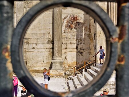 Athens/Greece - July 17 2019: Tourist posing for photo in  Hadrian's Library, archaeological site in Athens Greece. Framed through the railings.のeditorial素材