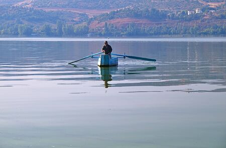 Kastoria/Greece - September 25, 2011: Orestiada lake, senior man paddles in blue boat.のeditorial素材