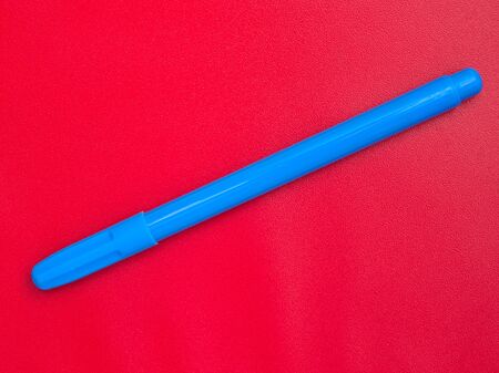 Blue marker isolated on red background, diagonal placement.の写真素材