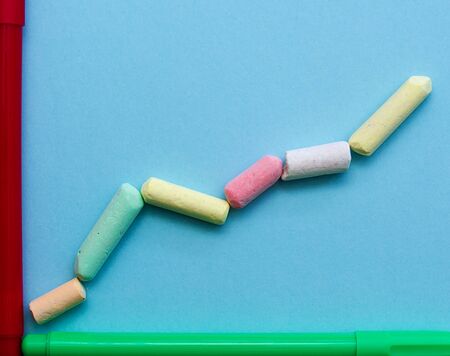 Uptrend line graph made with colorful Chalk pieces and markers on light blue background, back to school concept.の写真素材