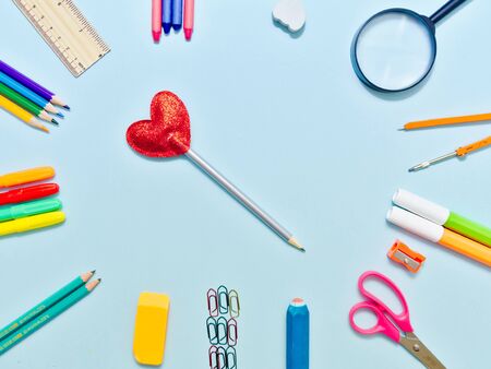 Colorful  school suplies in circle arrangement against light blue background with copy space.の写真素材