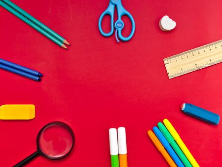 Colorful school supplies in circle arrangement on red background, back to school concept.の写真素材