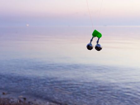 Fishing rod bell, on fishing line with beach background, sunrise time.の写真素材