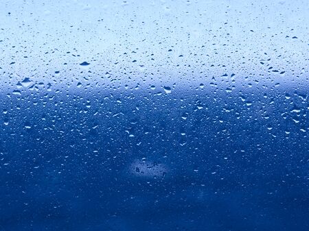 Water drops on window glass, sea and horizon line behind glass.の写真素材