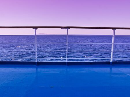 Ferry deck and railings with sea and horizon line background. Sunset / sunrise time beautiful purple sky.の写真素材