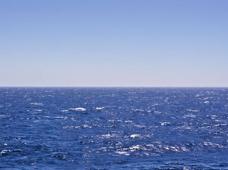Wavy deep blue sea and sky. Horizon line in the middle of the frame.の写真素材