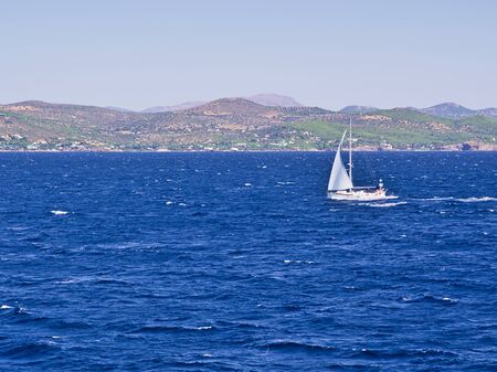 Sailboat at Aegean sea, background with island hills.の写真素材