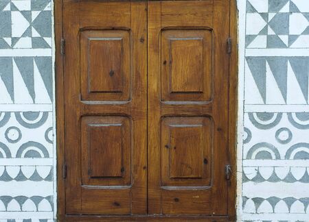 Wooden window and traditional geometrical decorative shapes on building exterior wall, Pyrgi village, Chios island, Greece.の写真素材